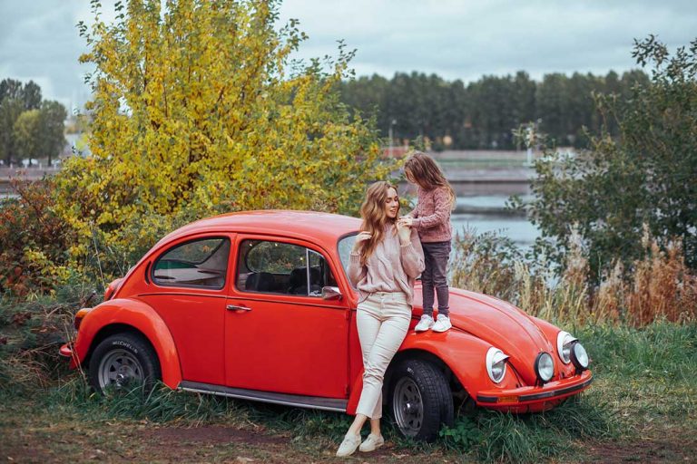 mother-and-little-daughter-relaxing-and-having-fun-in-countryside-on-camper-van-vacation-with-red-retro-car